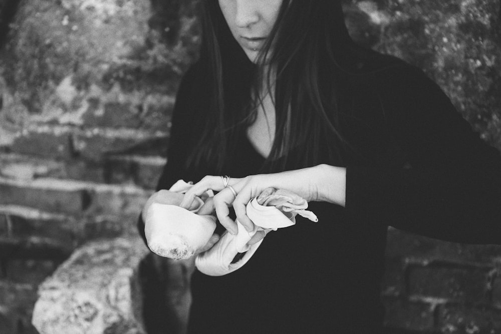 a black and white photo of a woman holding a flower