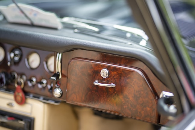 Close-up of a sleek car-play box plugged into a classic car dashboard.