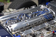 Shiny new spark plugs displayed with a blurred background of engine parts.