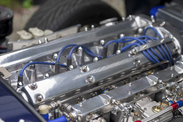 Close-up of a sleek engine block with polished metallic components reflecting light in a dark garage.