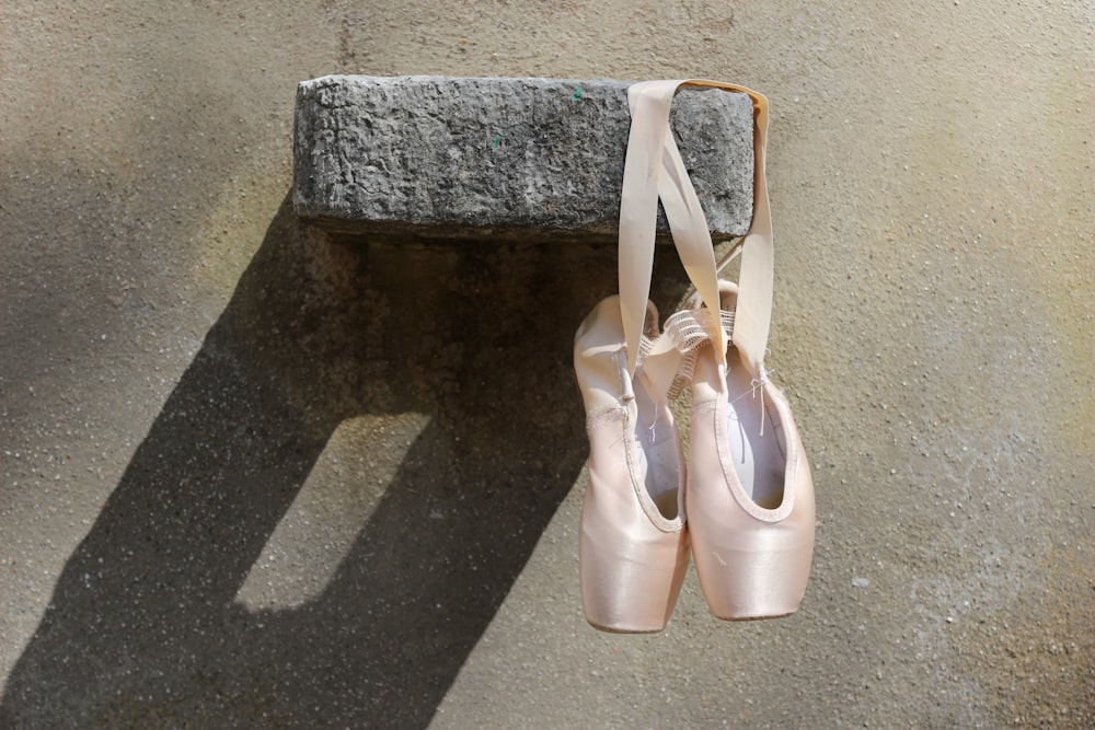 a pair of ballet shoes sitting on a stone bench