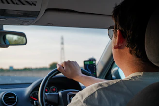 a man driving a car with a cell phone in his hand