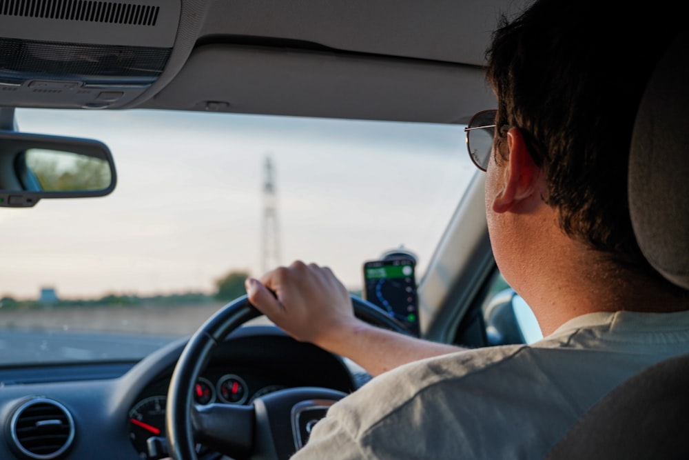 a man driving a car with a cell phone in his hand