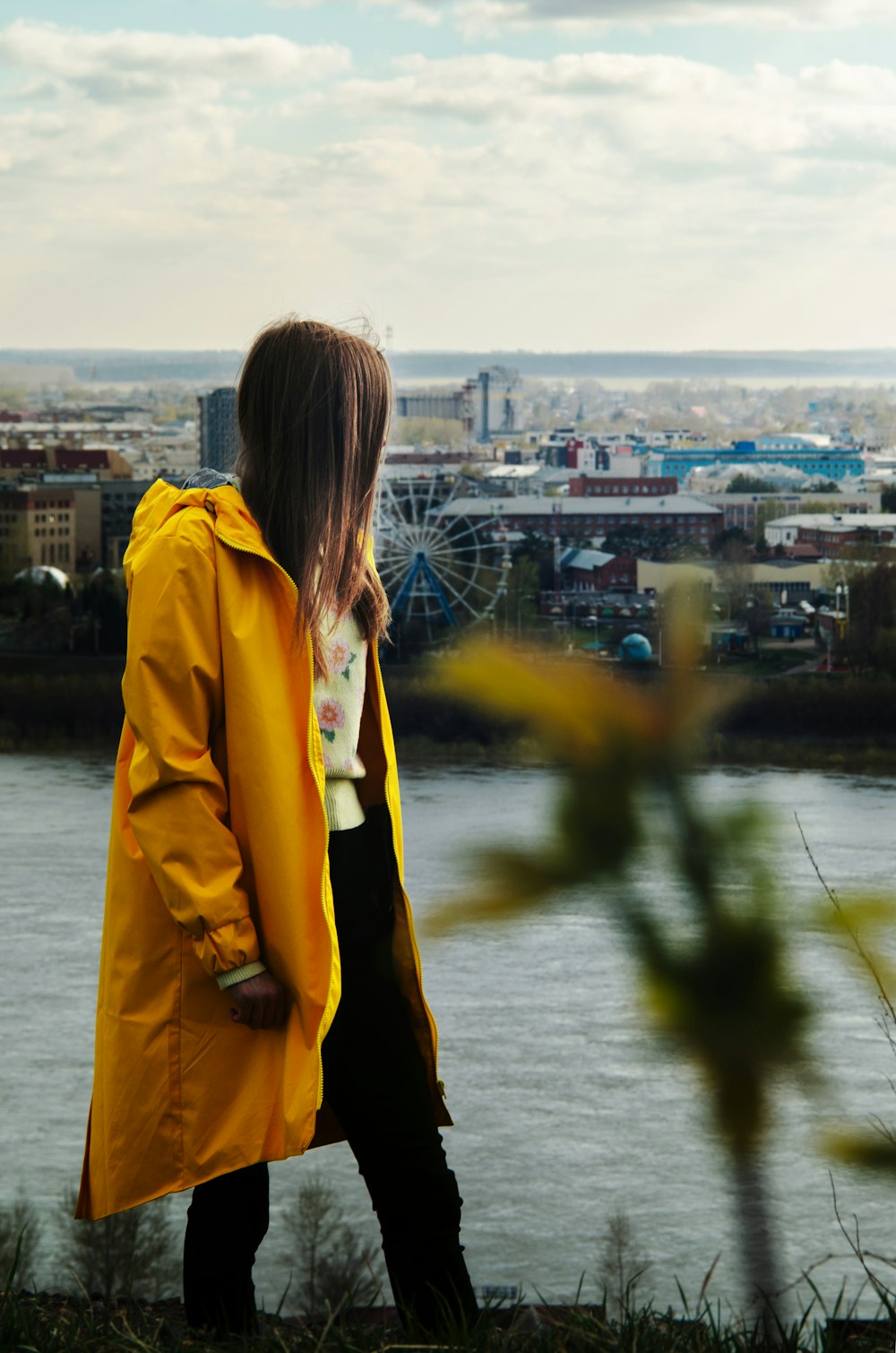 a woman in a yellow raincoat looking out over a city