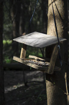 Close-up of a handcrafted bird feeder made of engineered wood with hanging seeds