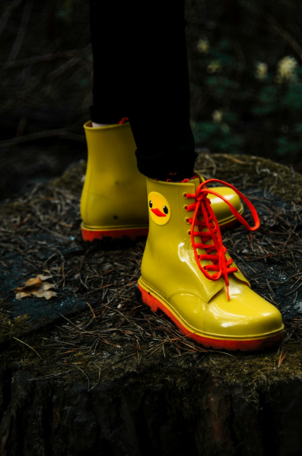 a person wearing yellow rain boots with red laces