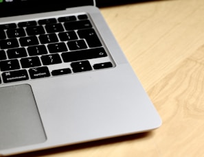 Close-up of a sleek laptop with a teal backlit keyboard on a wooden desk.