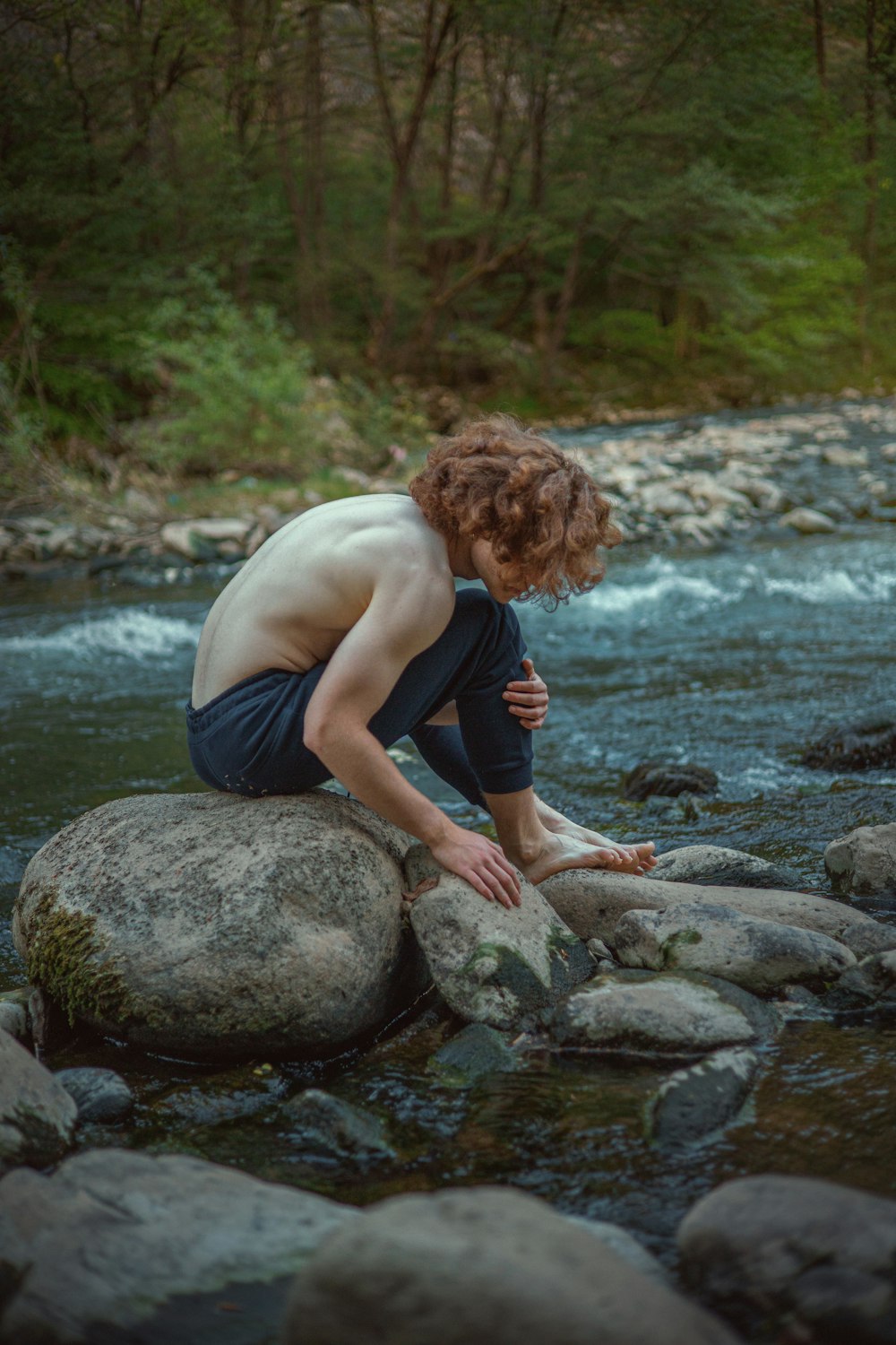 a man sitting on a rock in a river