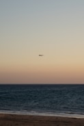 A scenic beach resort with a plane flying overhead at sunset