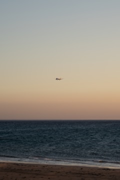 A scenic beach resort with a plane flying overhead at sunset