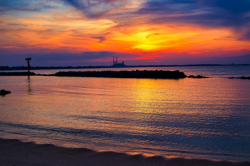 the sun is setting over the water at the beach