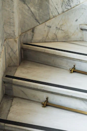 Close-up of a luxurious marble staircase with polished brass handrails in a modern home.