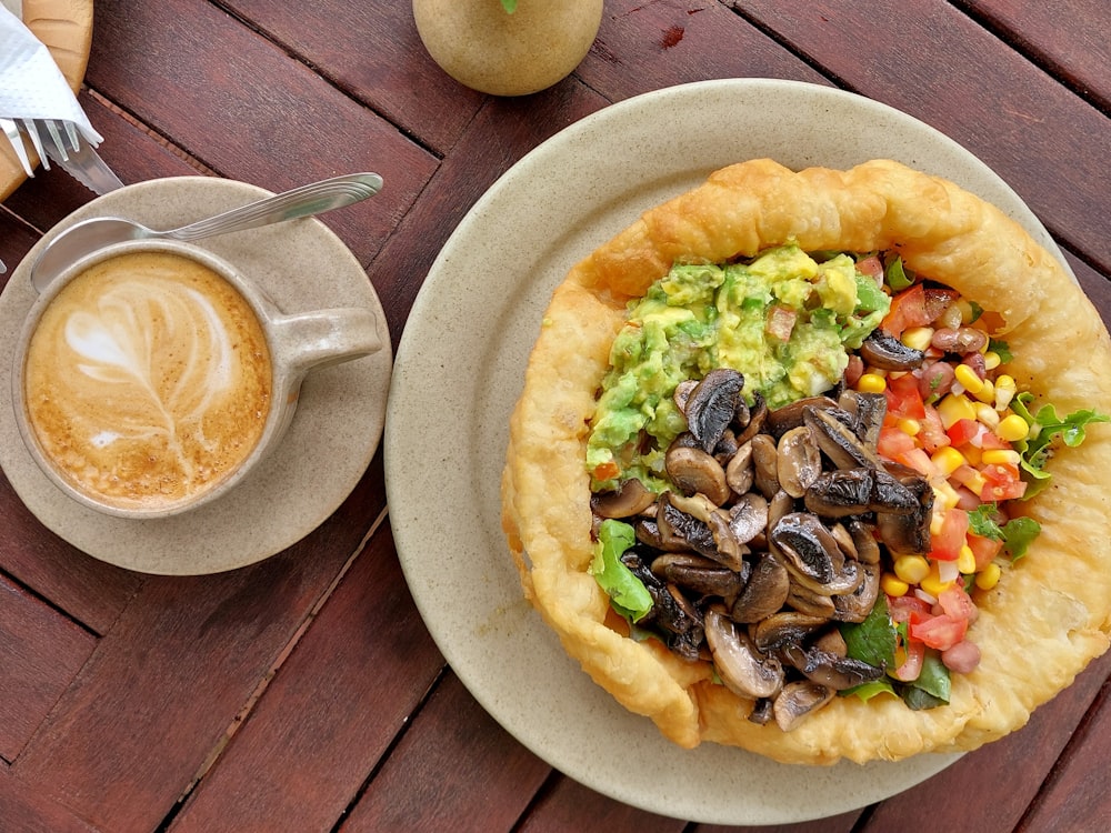 a plate of food on a table next to a cup of coffee