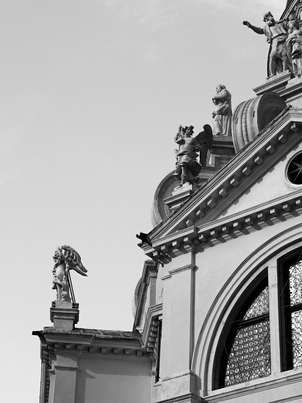a black and white photo of a building with statues on top