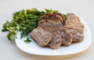 a white plate topped with slices of meat and parsley