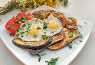 a white plate topped with fried eggs and vegetables