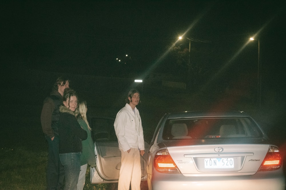 a group of people standing next to a car