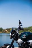 A motorcycle parked beside a tranquil lake surrounded by trees.