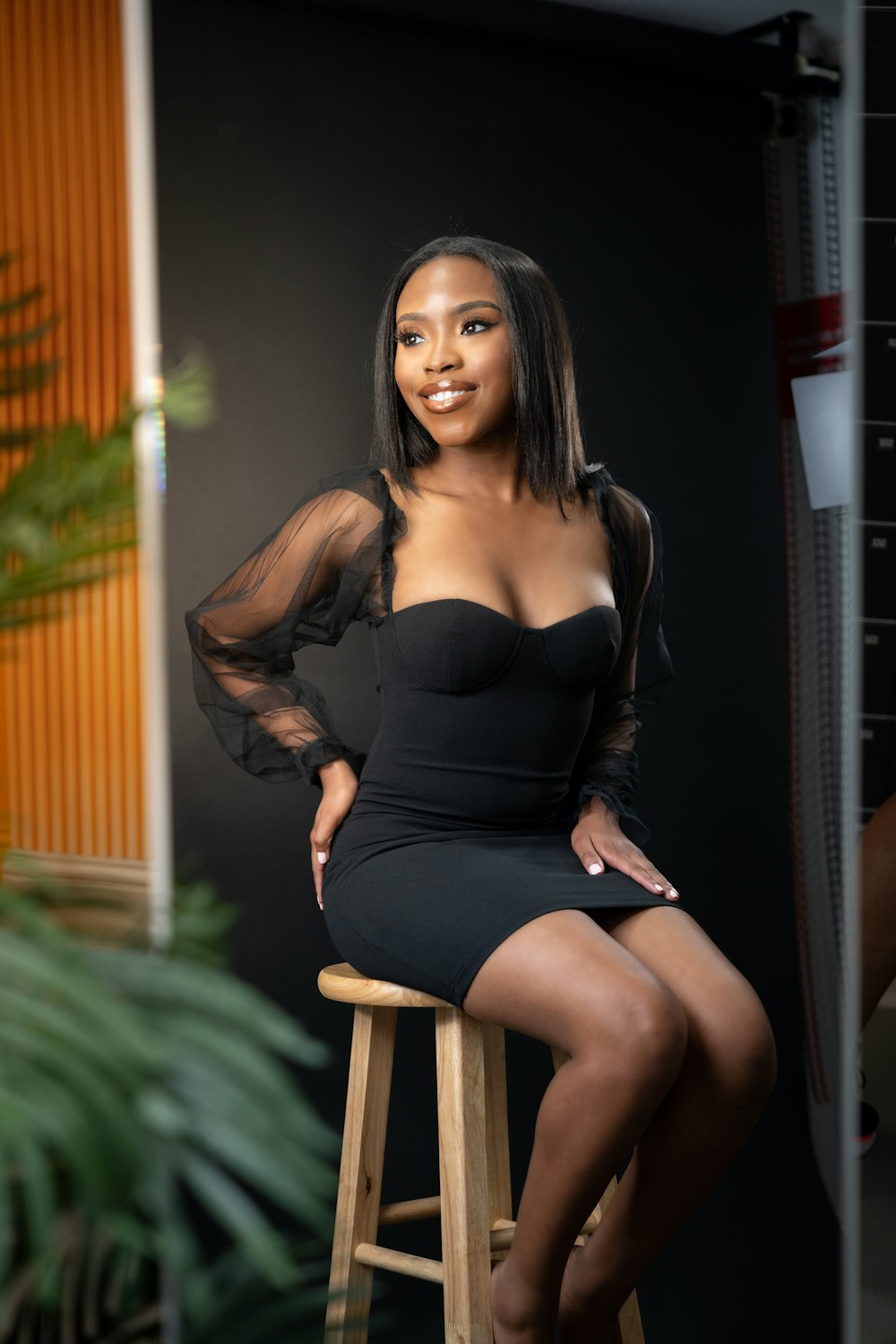 a woman in a black dress sitting on a stool