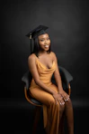 a woman in a graduation gown sitting on a chair
