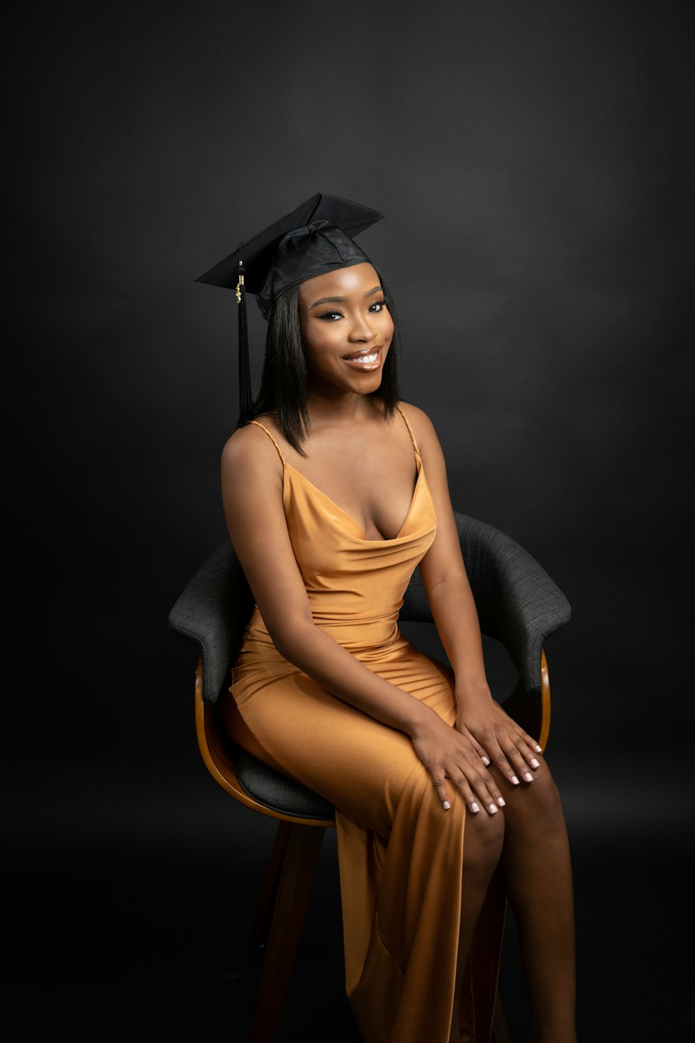 a woman in a graduation gown sitting on a chair