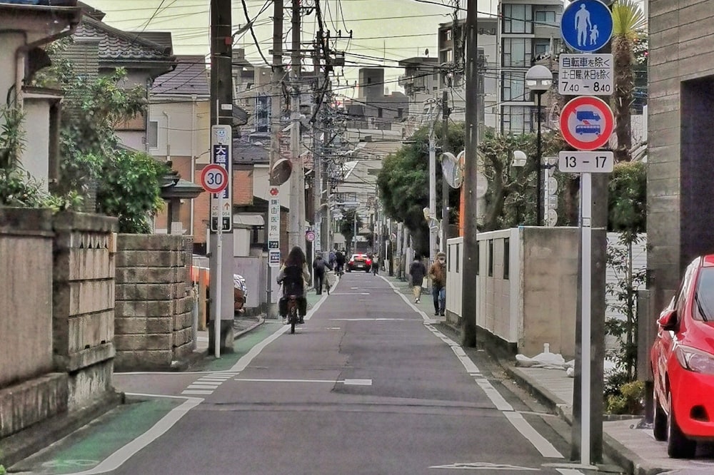 a person riding a bike down a street next to a red car