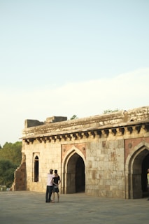 Two people embracing with the backdrop of a historic stone archway along the Camino route.