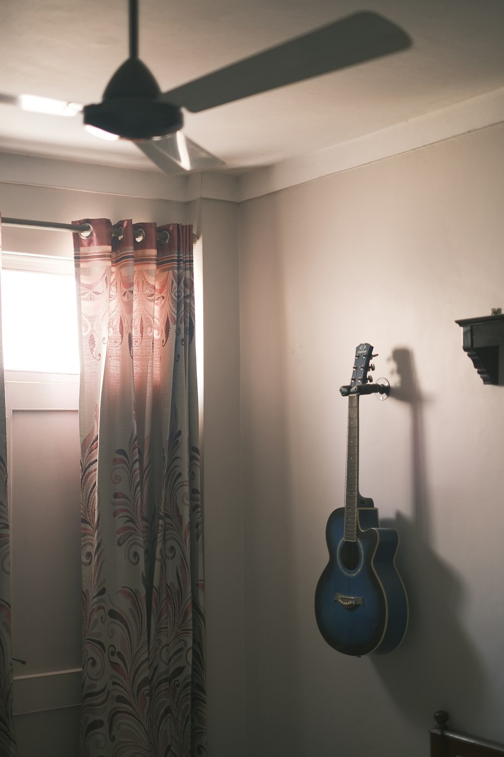 a guitar hanging on a wall next to a window