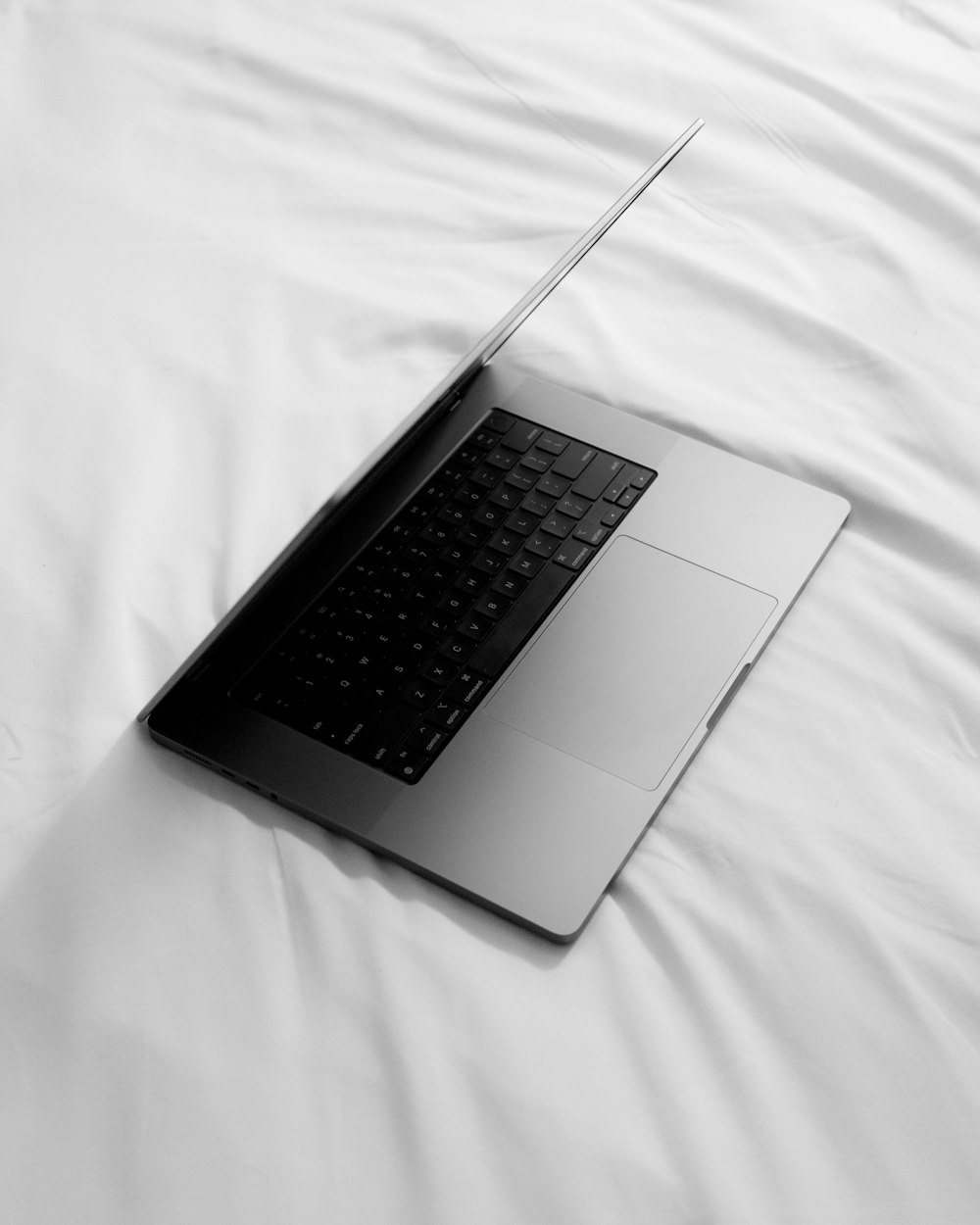 Una foto in bianco e nero di un computer portatile su un letto