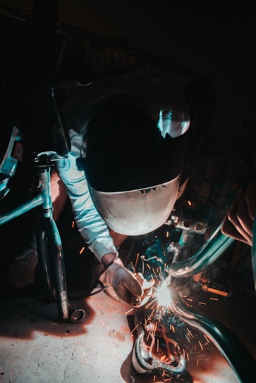 A skilled welder working with protective gear in an industrial metal workshop.
