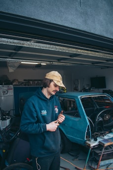 A locksmith using tools to unlock a car door in a garage.