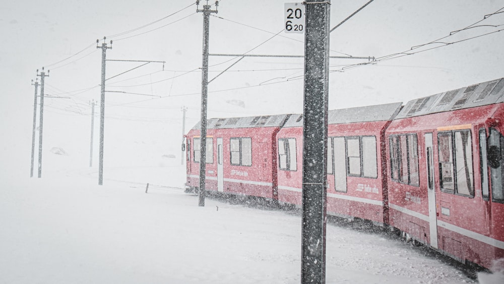 a red train traveling down train tracks covered in snow