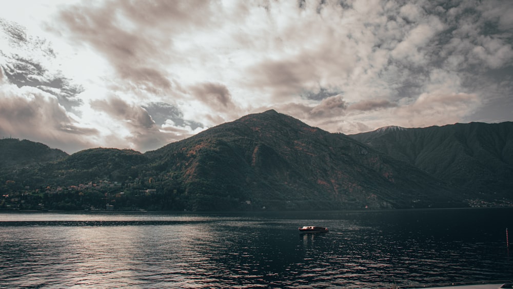 a boat floating on top of a lake under a cloudy sky