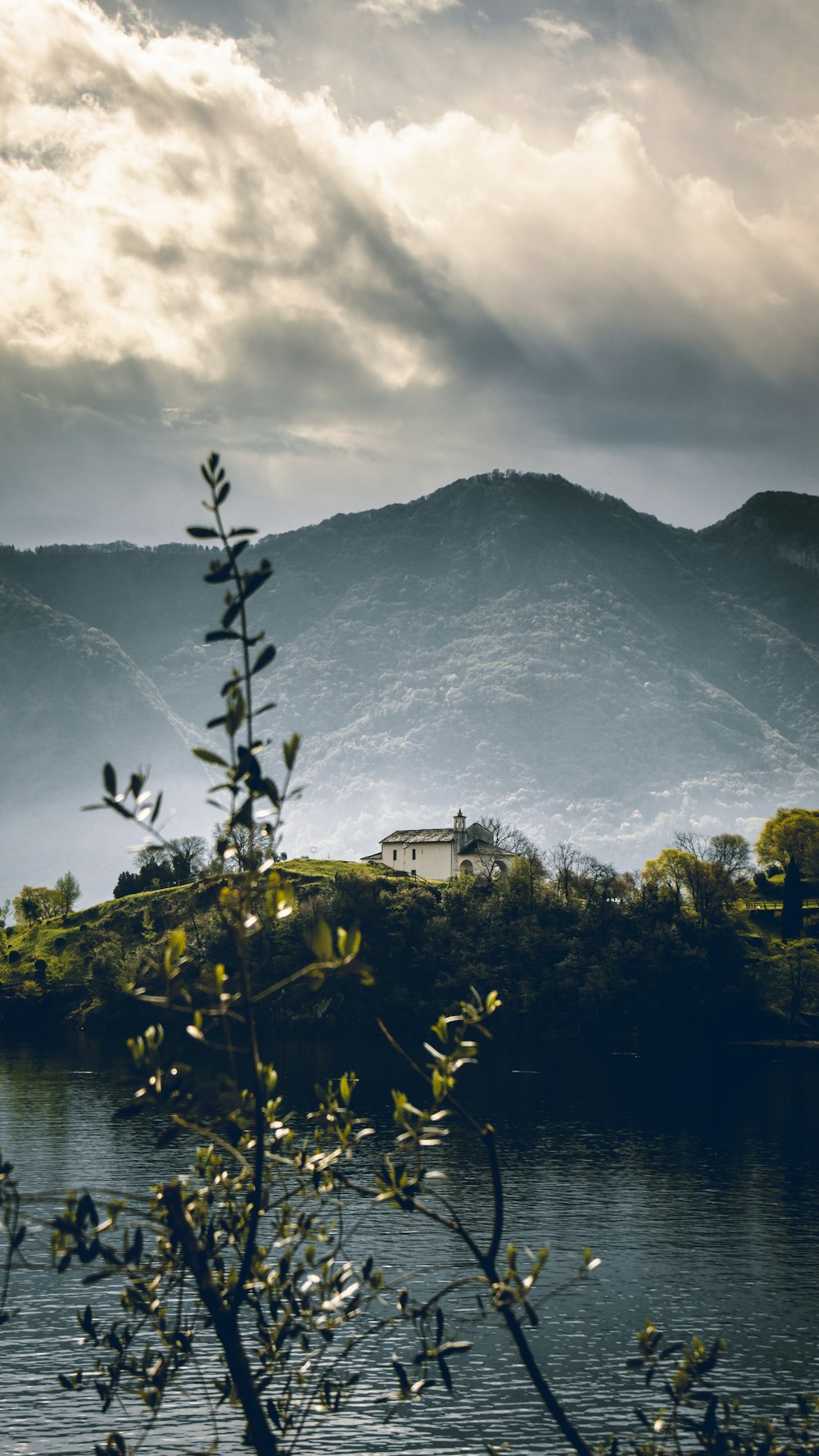 a lake surrounded by mountains under a cloudy sky