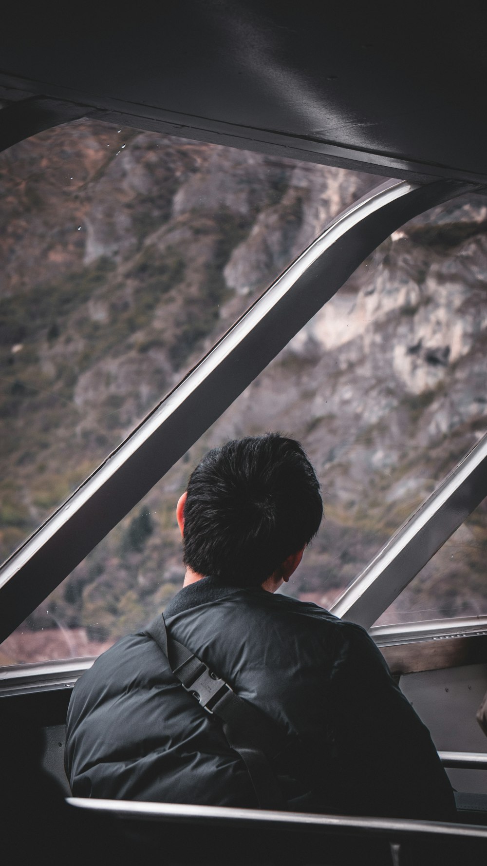 a man looking out a window at a mountain