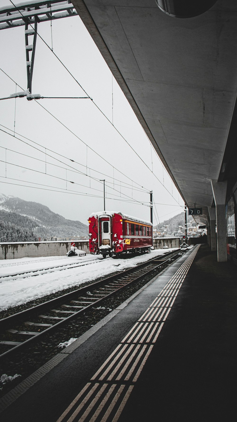 a red train traveling down train tracks next to a snow covered mountain