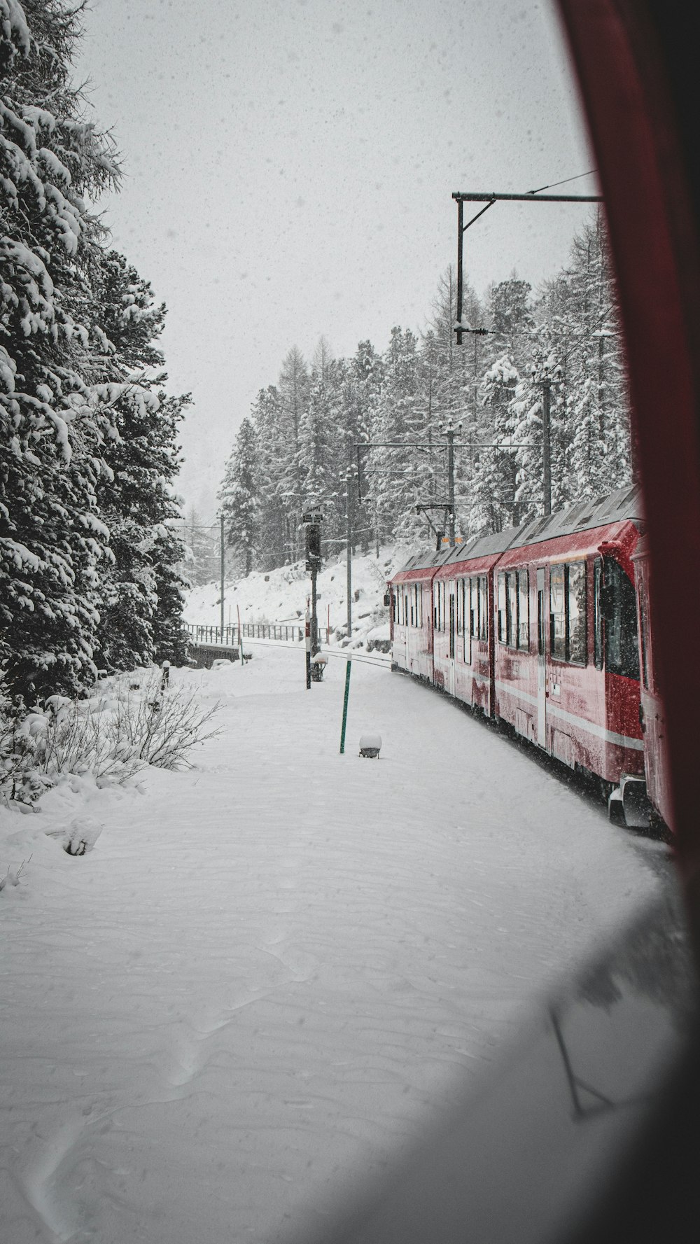 a red train traveling through a snow covered forest