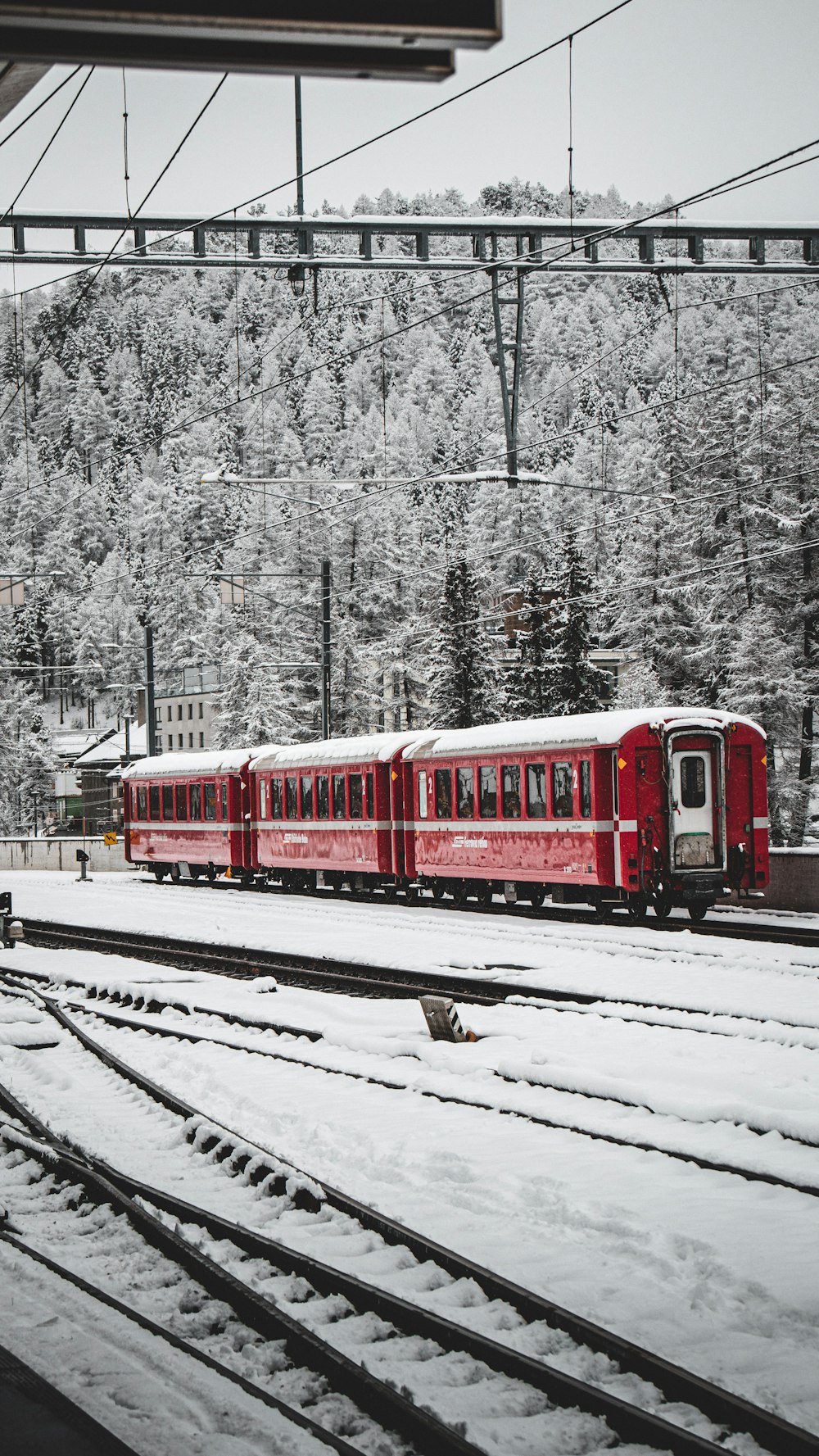 a red train traveling down train tracks next to a forest