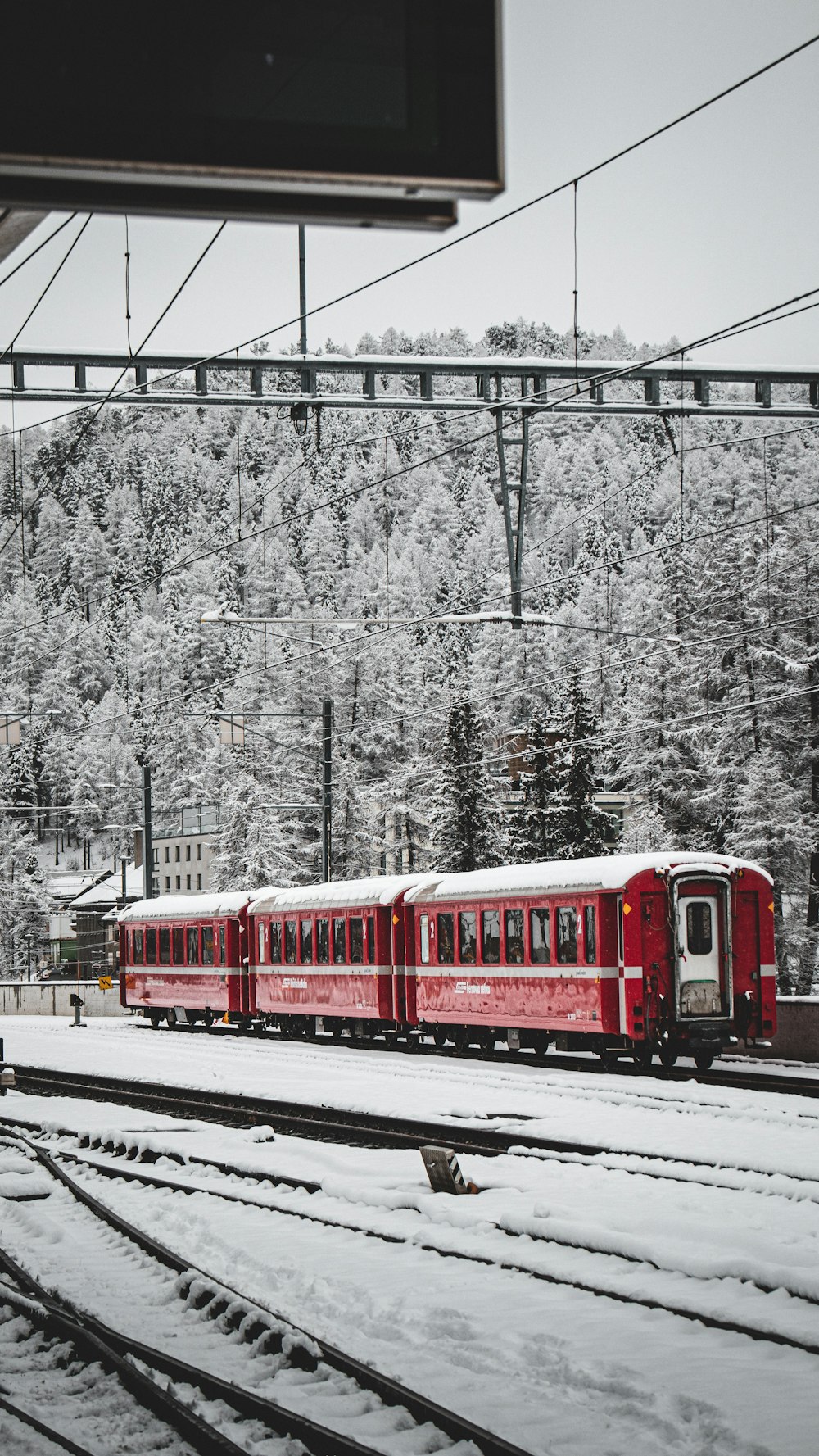 a red train traveling down train tracks next to a forest