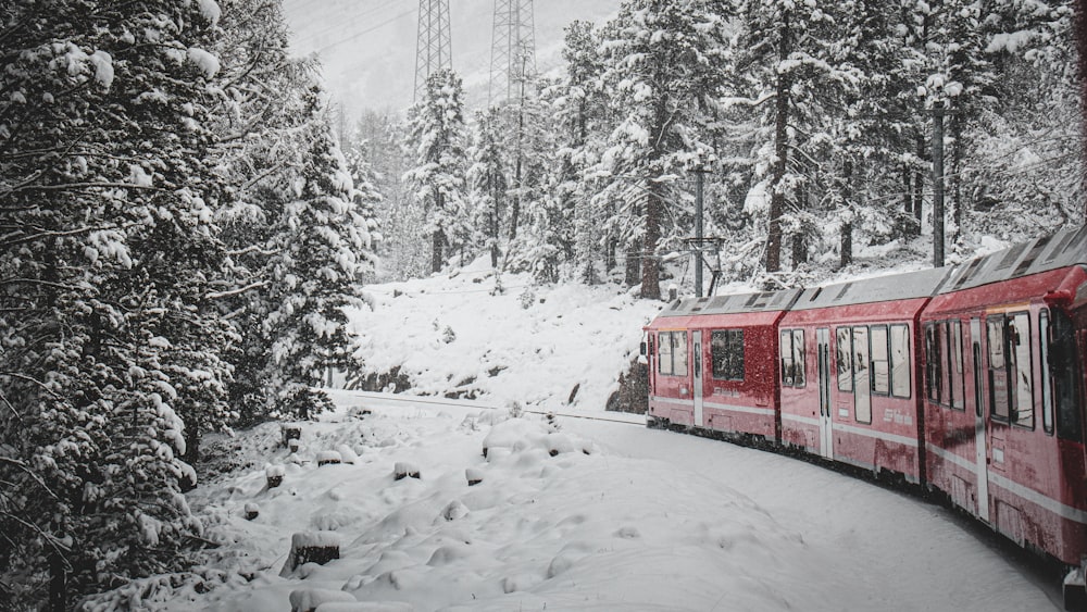 a red train traveling through a snow covered forest