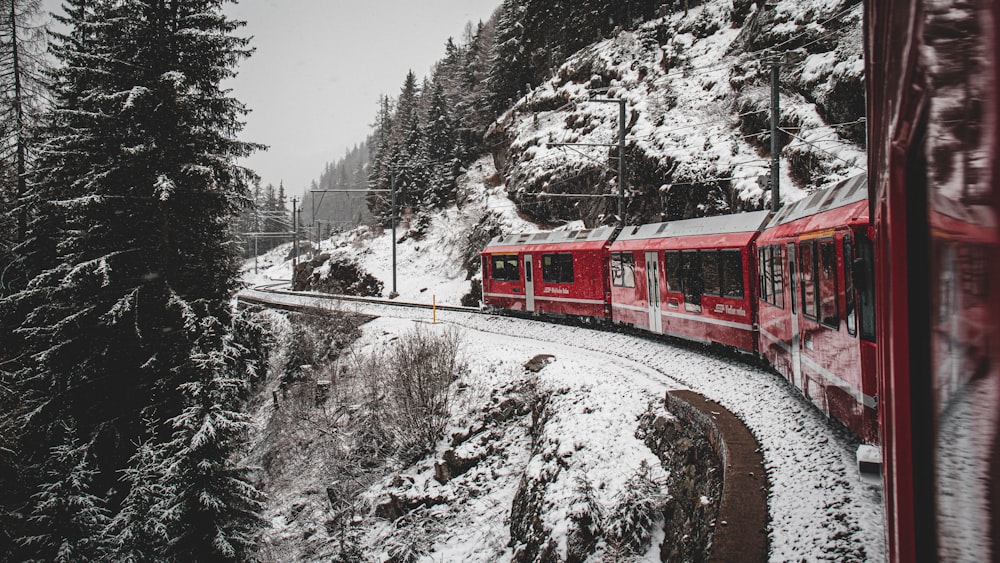 a red train traveling through a snow covered forest