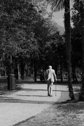a black and white photo of a man walking down a path