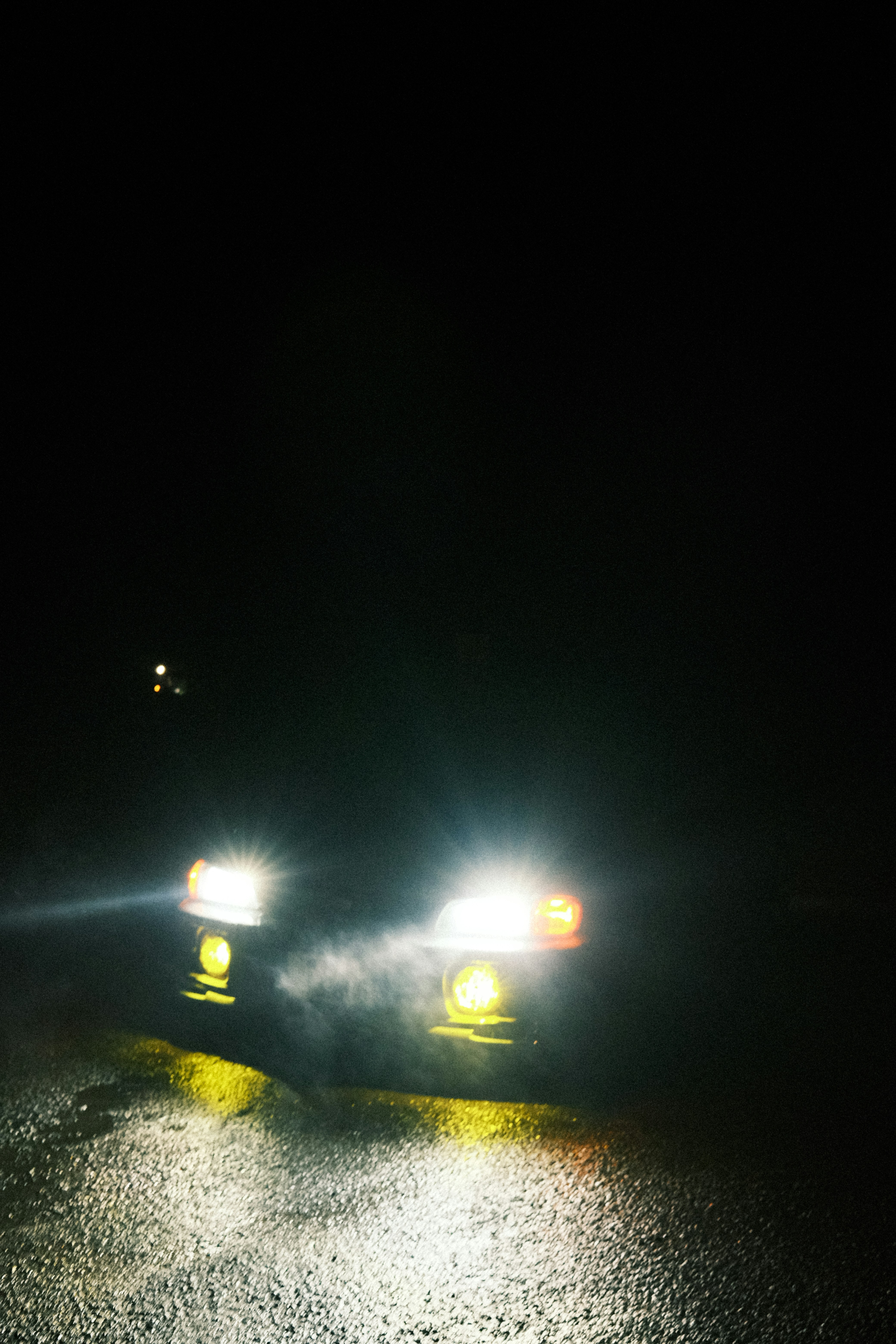 a couple of cars driving down a street at night