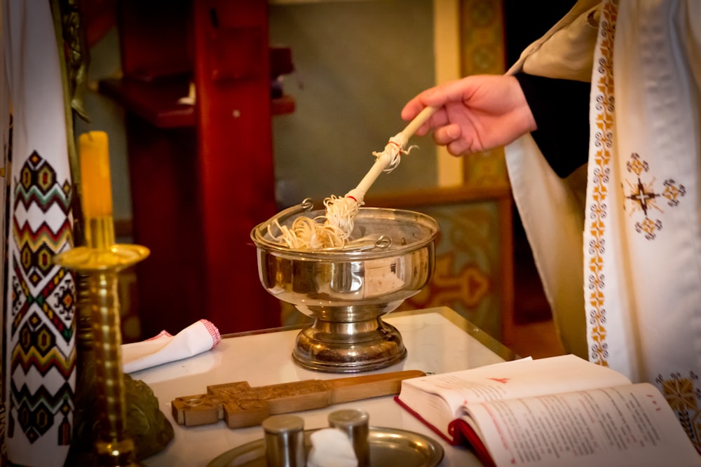 a person holding a spoon over a bowl of noodles