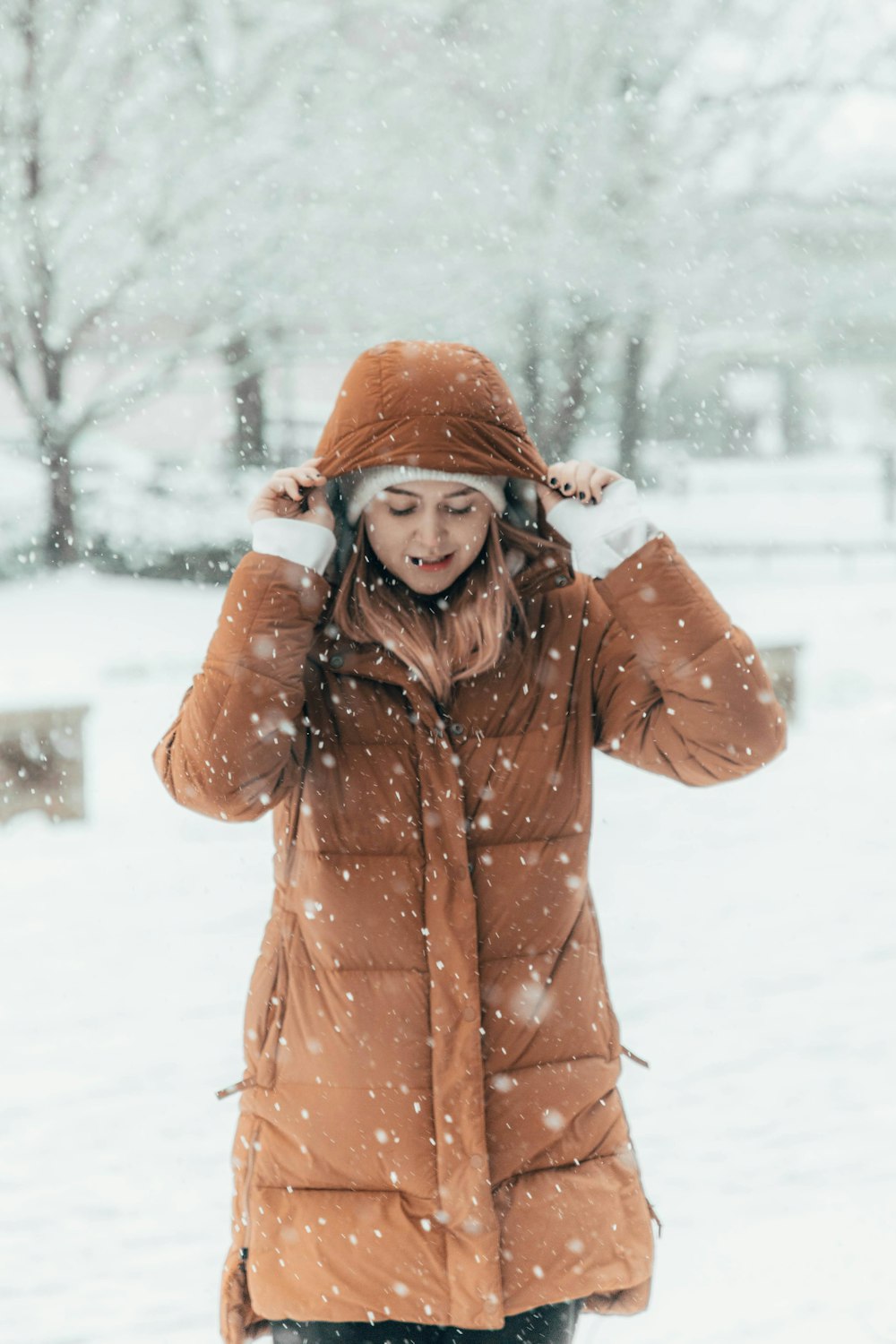 eine frau, die im schnee steht, trägt einen braunen mantel