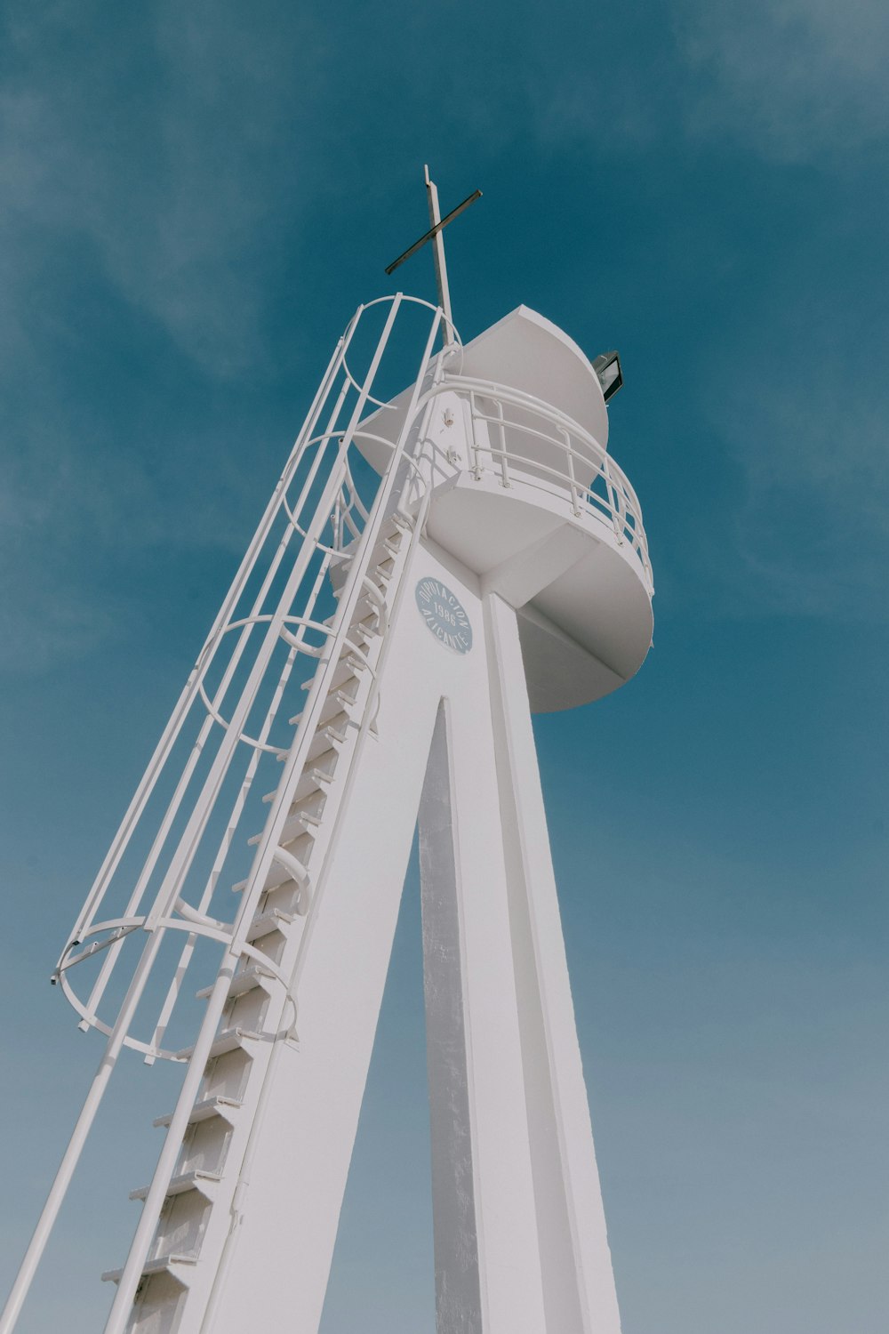 Una alta torre blanca con una cruz en la parte superior