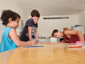 Children participating in a traditional craft workshop inside a cozy community hall