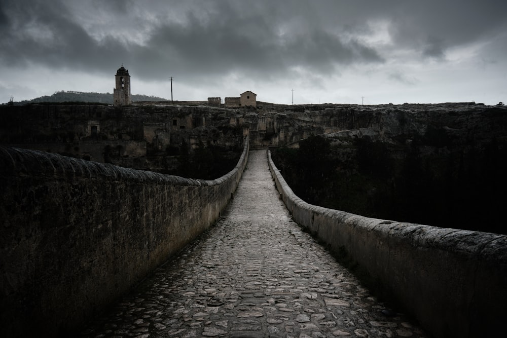 a stone walkway leading to a castle under a cloudy sky