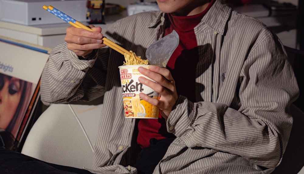 a man holding a cup of cereal and a toothbrush