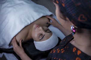a woman laying in bed with a towel on her head